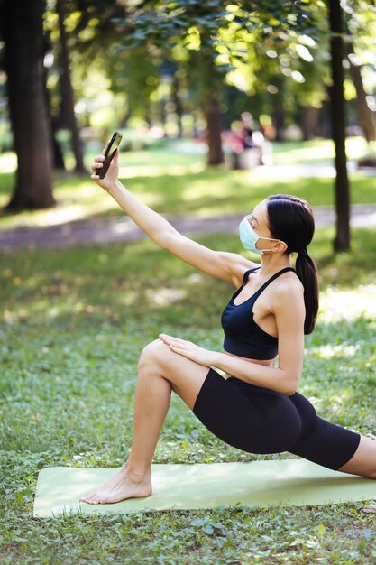 La ragazza di giovane sport prende selfie su uno smartphone all'aperto sulla natura. Concetto di stile di vita sano.