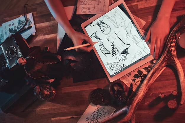 La ragazza di talento sta disegnando su una tavoletta digitale mentre è seduta nel suo accogliente studio.