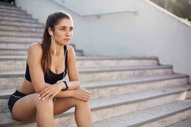 La ragazza dimentica i problemi durante il jogging, il corridore si siede all'aperto su sta