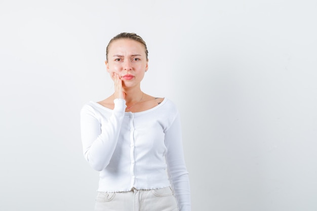 La ragazza dolorante sta mostrando il suo mal di denti su sfondo bianco