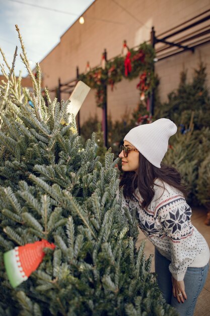 La ragazza elegante acquista un albero di Natale.