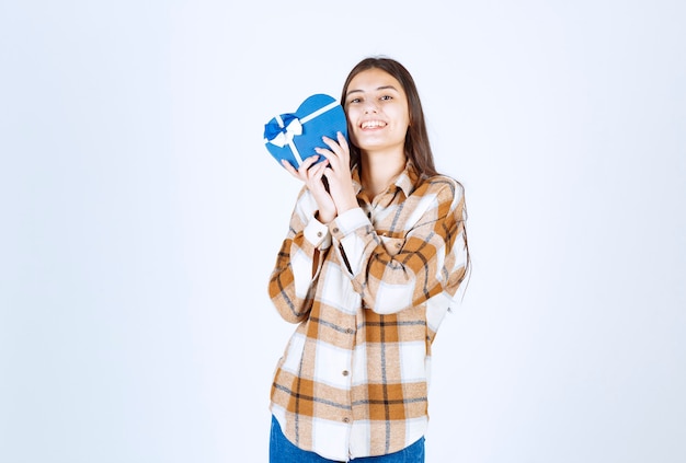 la ragazza felice abbraccia il regalo a sorpresa sul muro bianco.