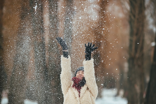 La ragazza felice gettando neve