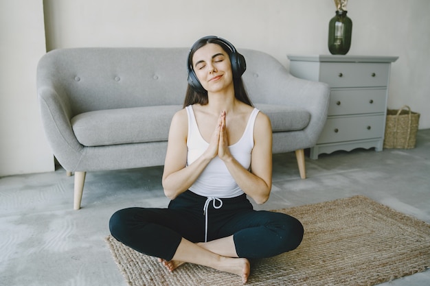 La ragazza felice in cuffie ascolta la musica a casa