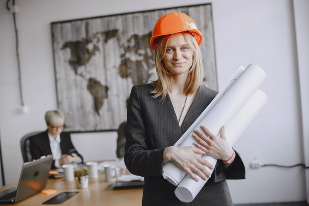 La ragazza firma i documenti. Signora in un casco rosso. Managerl che lavora in ufficio.