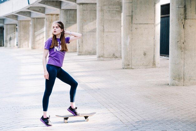 La ragazza guarda indietro mentre skateboarding