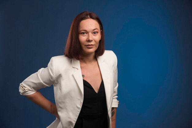 La ragazza in blazer bianco fa nella posa positiva.