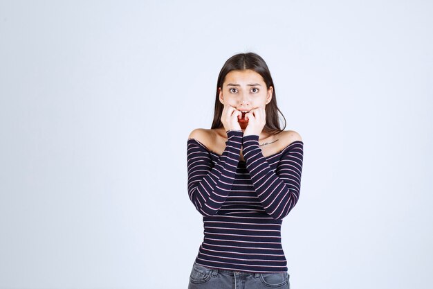 La ragazza in camicia a righe sembra terrorizzata e spaventata.