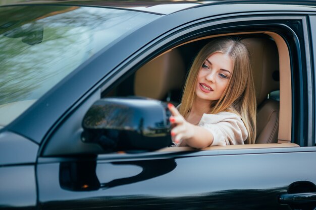 La ragazza in macchina organizza mirrow della vista posteriore