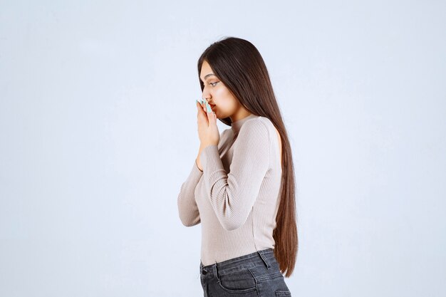 La ragazza in maglione grigio sente un cattivo odore e copre il naso.