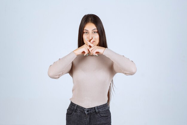 La ragazza in maglione grigio sente un cattivo odore e copre il naso.