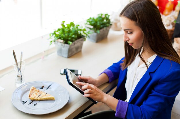 La ragazza in un caffè legge qualcosa sulla tavoletta