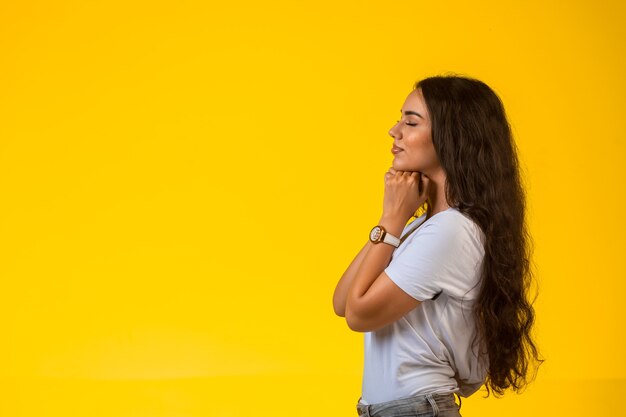 La ragazza mette le mani sotto il mento e prega, vista di profilo.