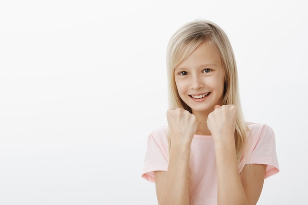 La ragazza mostrerà a tutti i suoi punti di forza. allegra adorabile figlia in maglietta rosa, alzando i pugni chiusi, in piedi in posa da boxe, scherzando e sorridendo ampiamente, difendendo