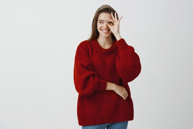 La ragazza non smette mai di prendersi cura del suo ragazzo. Fiduciosa gioiosa donna caucasica in maglione rosso sciolto, mostrando bene o grande segno sopra l'occhio e guardando da parte con un sorriso felice