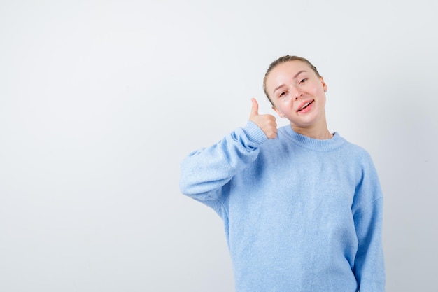 La ragazza piacevole sta mostrando un segno eccellente su priorità bassa bianca