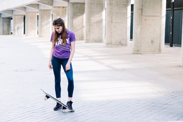 La ragazza poggia il piede sul suo skateboard