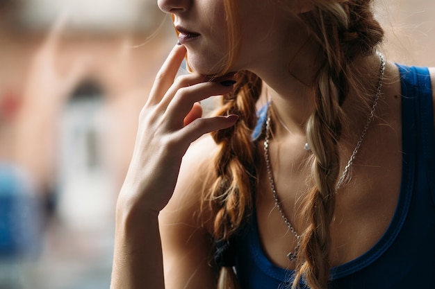 La ragazza premurosa in un vestito di forma fisica posa prima di una finestra in una palestra