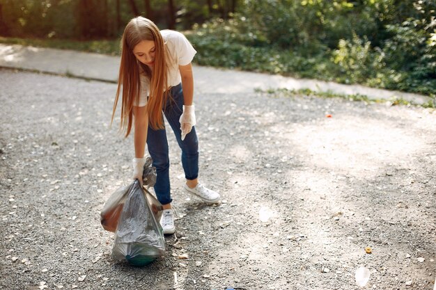 La ragazza raccoglie l'immondizia nei sacchetti di immondizia in parco
