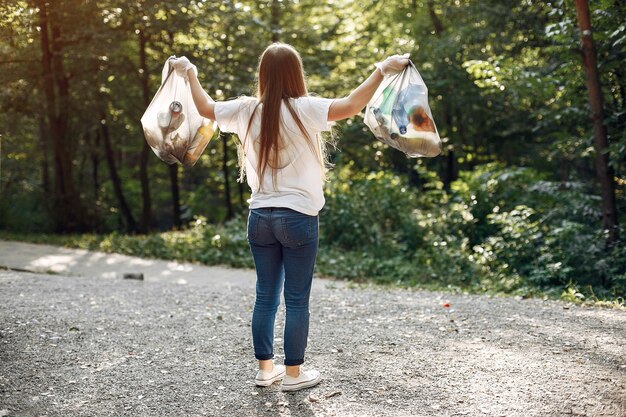 La ragazza raccoglie l'immondizia nei sacchetti di immondizia in parco