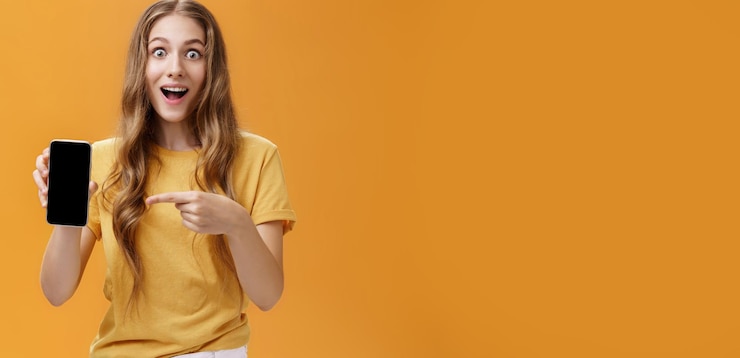 Foto gratuito la ragazza sorpresa con le fantastiche caratteristiche dello smartphone ritratto di una bella snella europea felice e stupita