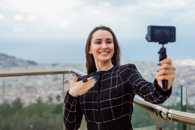 La ragazza sorridente del blogger si sta facendo un selfie mostrando il suo anello alla fotocamera sullo sfondo della vista della cittàxDxA