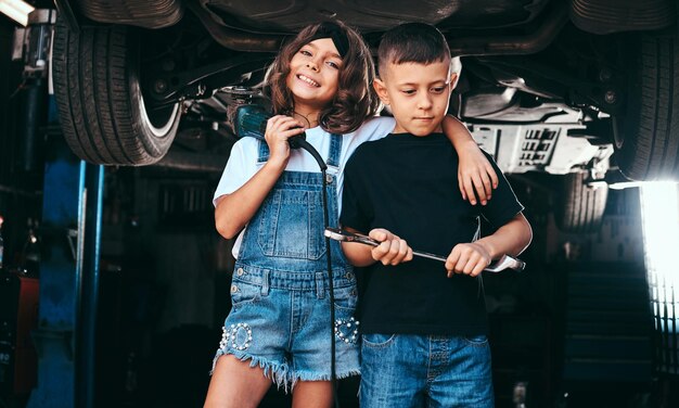 La ragazza sorridente e il ragazzo pensieroso stanno posando per il fotografo all'officina di servizio automatico.