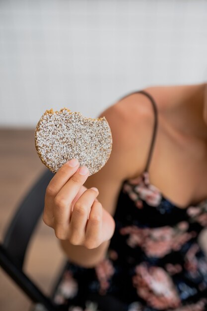 La ragazza sorridente felice tiene il biscotto in un caffè accogliente. Chiudi vista