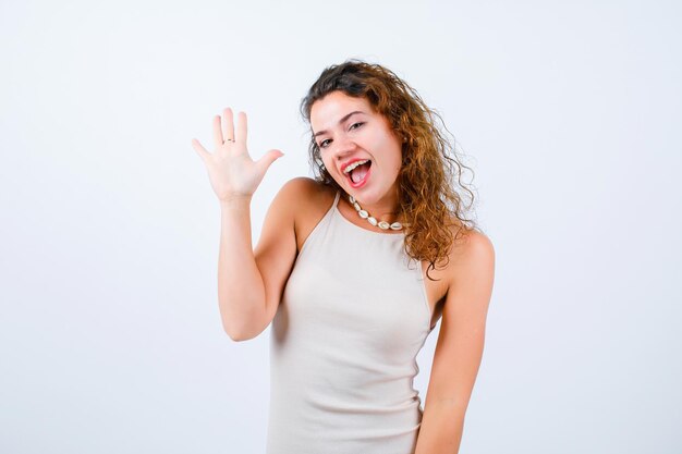 La ragazza sorridente sta alzando la sua manciata su fondo bianco