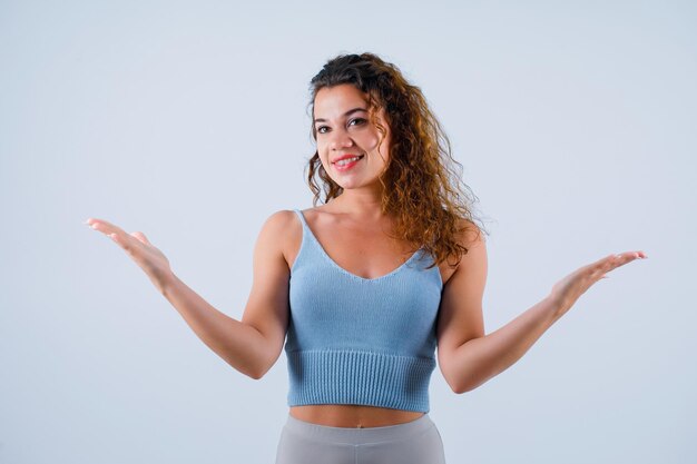 La ragazza sorridente sta distogliendo lo sguardo aprendo le mani su sfondo bianco