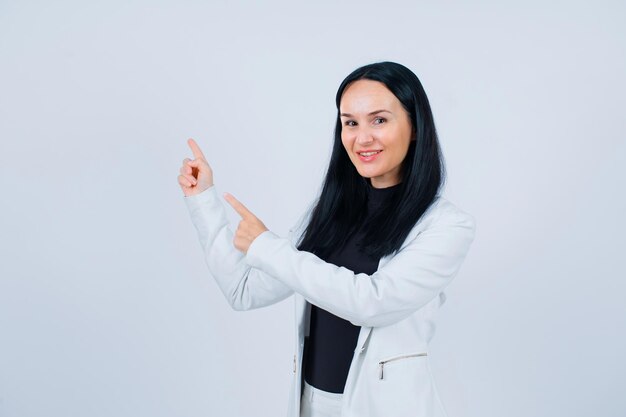 La ragazza sorridente sta puntando a sinistra con gli indici su sfondo bianco