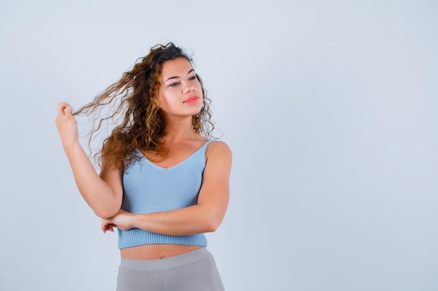 La ragazza sta distogliendo lo sguardo tenendo i capelli su sfondo bianco