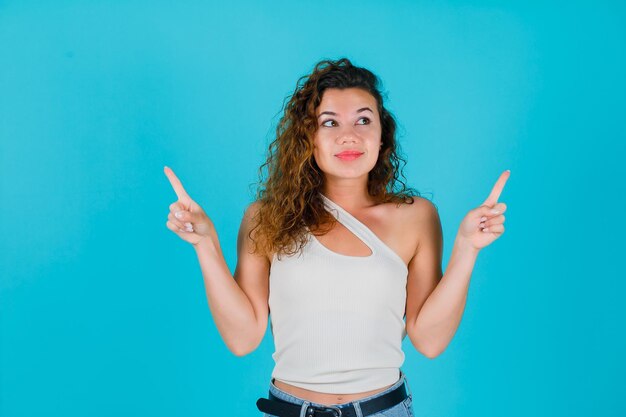 La ragazza sta guardando bene e punta verso l'alto con gli indici su sfondo blu