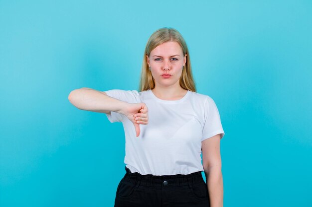 La ragazza sta mostrando un gesto di antipatia con il pollice su sfondo blu