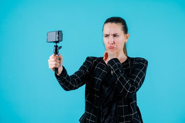 La ragazza sta prendendo selfie mostrando il mimetismo piangente su sfondo blu