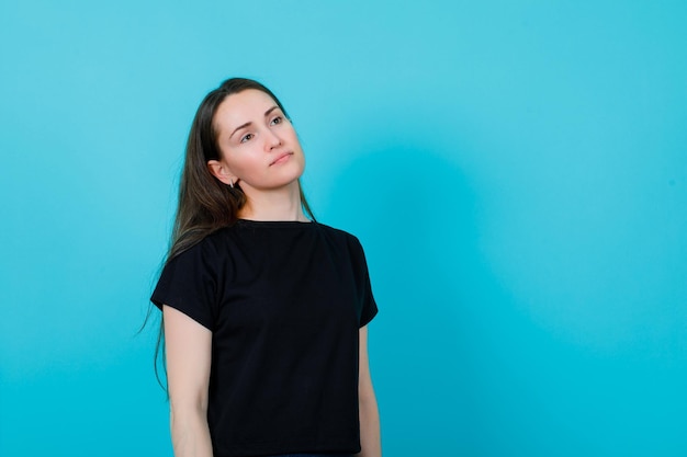 La ragazza stanca sta distogliendo lo sguardo su sfondo blu