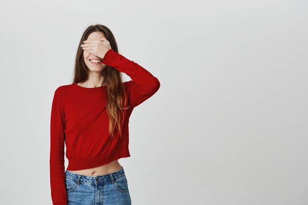 La ragazza sveglia con la fine di bello sorriso osserva con la mano, aspettando la sorpresa