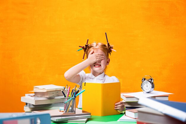 La ragazza teenager rossa con molti libri a casa. Colpo dello studio