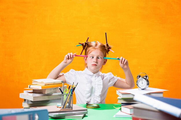 La ragazza teenager rossa con molti libri a casa.