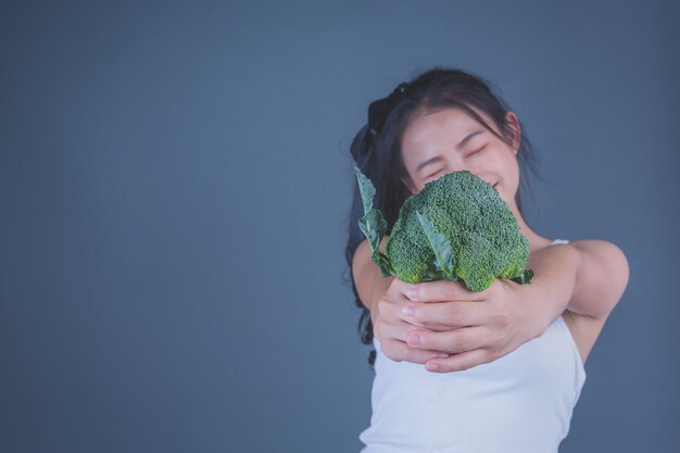 La ragazza tiene le verdure su uno sfondo grigio.