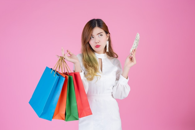 La ragazza tiene una shopping bag di moda e tiene un biglietto da un dollaro