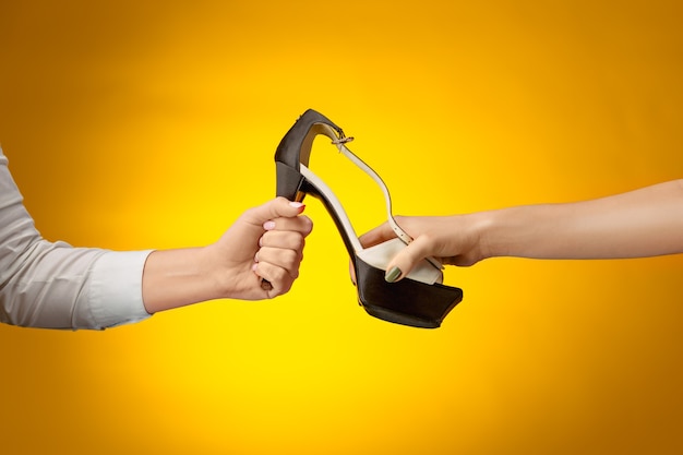 La scarpa femminile con donna e uomo sulle mani su carta gialla. Shopping e concetto di black friday