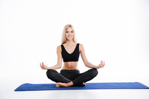 La seduta felice della donna di forma fisica fa gli esercizi di yoga