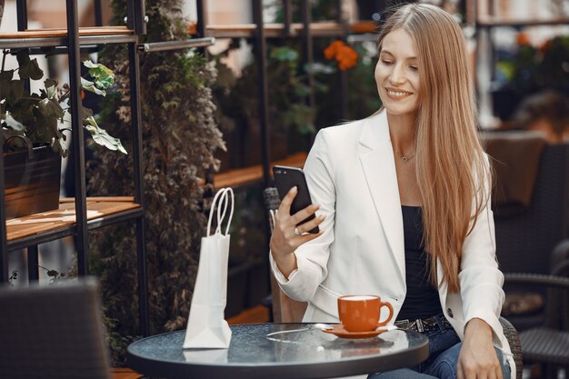 La signora beve un caffè. Donna seduta al tavolo. La ragazza usa un telefono.