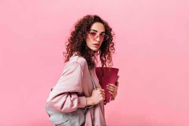 La signora con i capelli ondulati esamina la macchina fotografica e tiene i libri