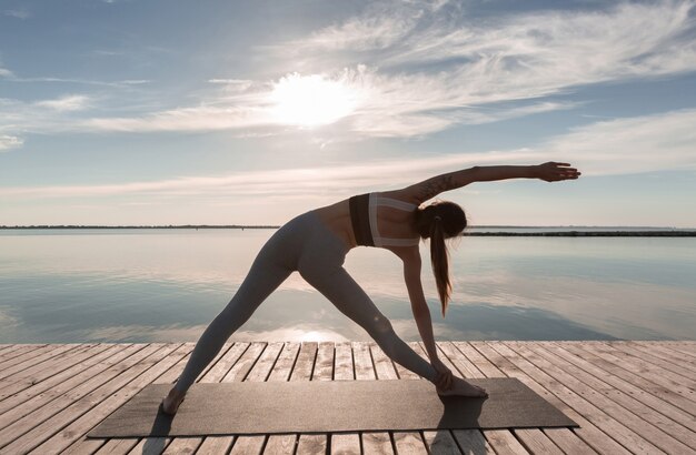 La signora dello sport che sta in spiaggia fa esercizi di yoga.