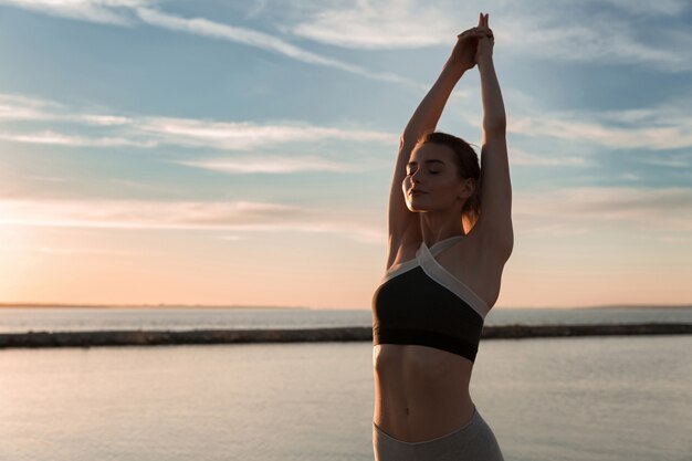 La signora dello sport in spiaggia fa esercizi di meditazione.