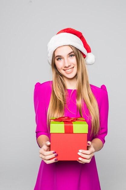 La signora felice divertente abbastanza sorridente in breve vestito rosa e cappello del nuovo anno tiene la sorpresa della scatola di carta nelle sue mani