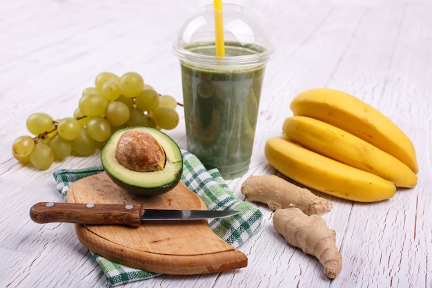 La smoothie verde con banane, calce, uva e avocado si trovano sul tavolo