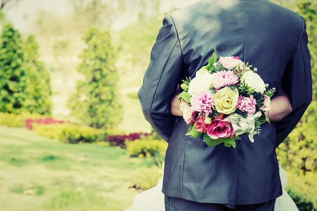 La sposa abbracciando sposo con bouquet in mano